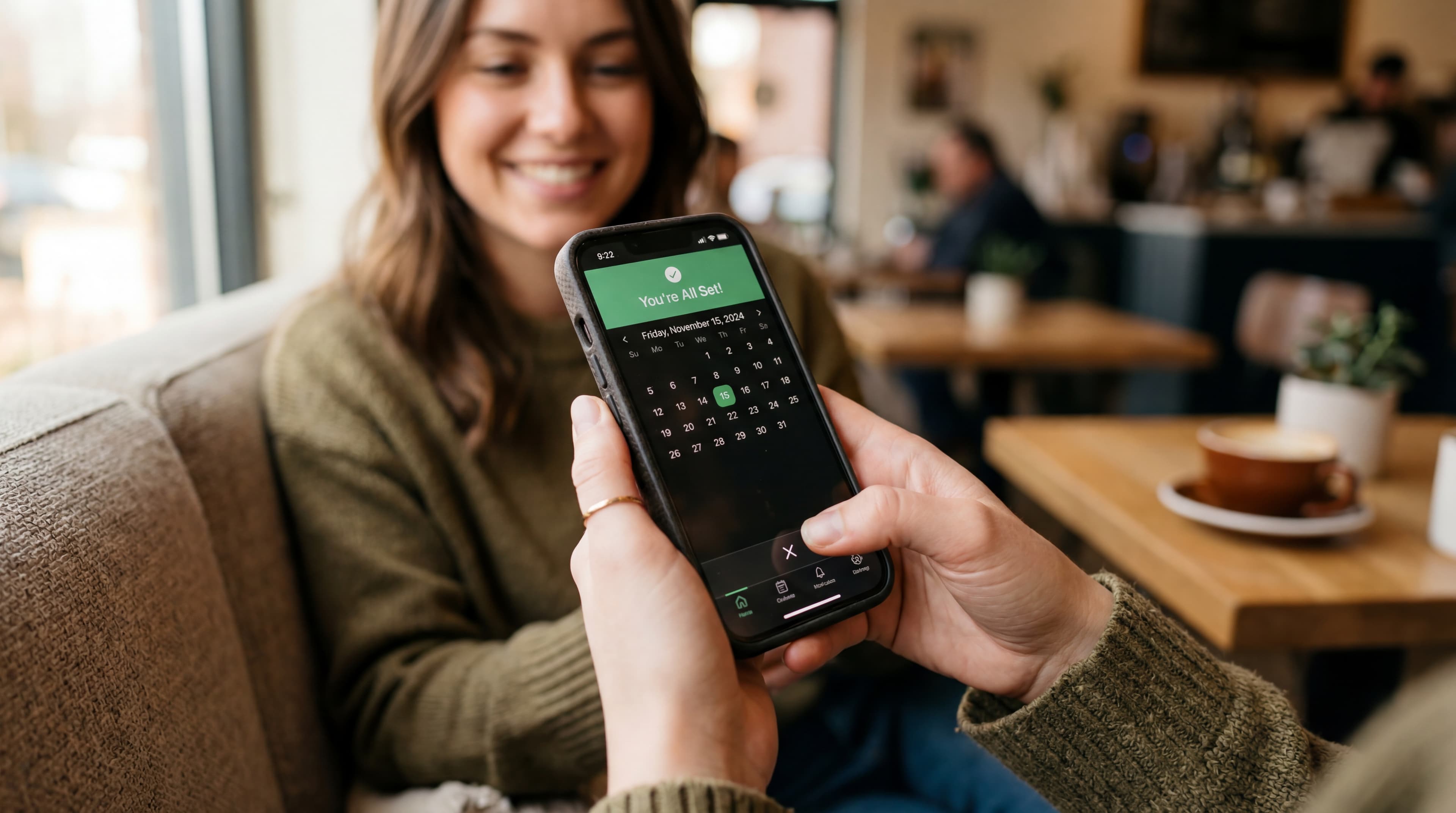 Learner showing a booking calendar on her phone in a café